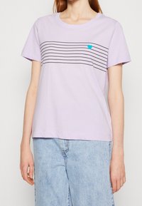 Lilla bomulds T-shirt med horisontale sorte striber og et lille blåt hjerte på venstre bryst. Normal pasform med korte ærmer.