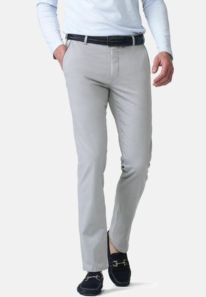 Man draagt lichtgrijze skinny broek, een zwarte geweven riem, een wit overhemd met lange mouwen en zwarte loafers, lopend naar voren.