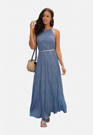 Maxikleid in Blau mit gepunktetem Muster, ärmellosem Design, tailliert und mit einem fließenden Rock, kombiniert mit einer geflochtenen Tasche und Sandalen.