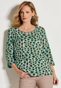 Top leopard print verde e beige in un morbido e leggero tessuto, con maniche a tre quarti e dettaglio a chiave nel collo.