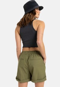 Svart ribbad crop top tillsammans med olivgröna vikbara shorts. Shortsen har en avslappnad passform och bakfickor. En svart bucket hat fulländar looken.