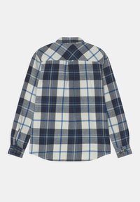 Kostkovaná košile s dlouhým rukávem v námořnické modři, šedé a bílé barvě. Má knoflíkový přední zapínání, zakřivený lem a detail hrušky na zadní straně. Bavlněná látka.