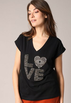 T-shirt noir à col en V mettant en avant des lettres en sequins argentés texturés formant le mot "AMOUR", avec un design en forme de cœur au centre. Manches courtes.