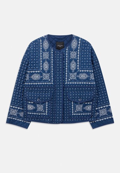 Giacca blu trapuntata con motivi bianchi a paisley e floreali, colletto rotondo, chiusura con bottoni e due grandi tasche a patta con bottoni.