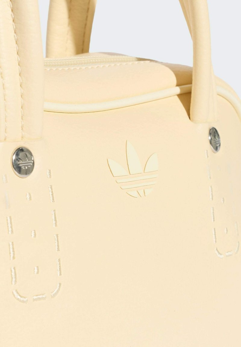 Borsa color crema Adidas con doppi manici, logo in rilievo, dettagli cuciti e rivetti in metallo ai lati.