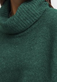 Maglione verde a maglia con colletto alto rigato e spesso. Il tessuto morbido presenta un motivo sottile e una vestibilità leggermente ampia.