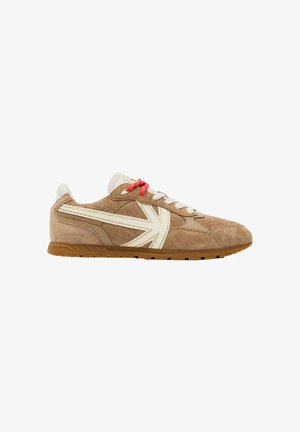 Zapatilla de ante marrón con cordones blancos y rojos, franjas laterales blancas y beige, y suela de goma color goma.