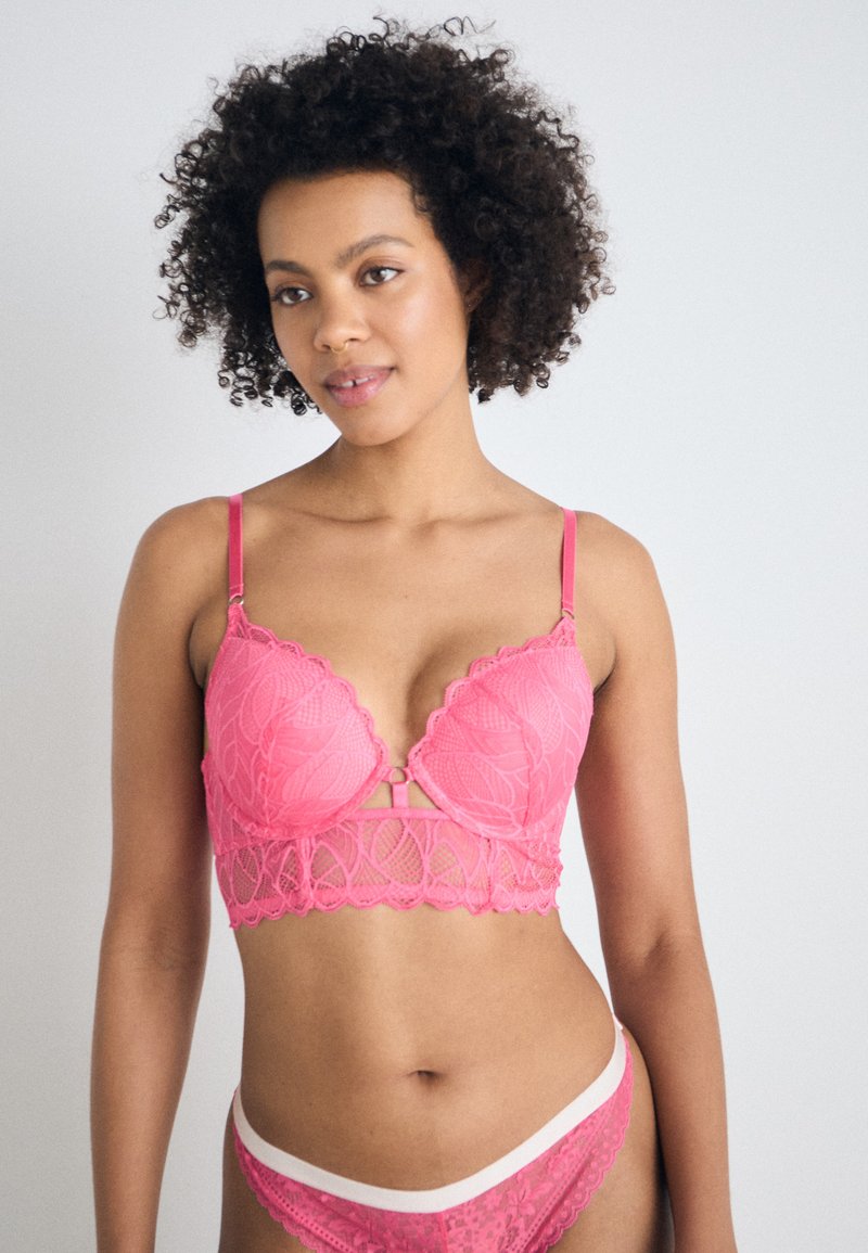Pink lace lingerie set featuring a bralette with scalloped edges, cutout detail, and adjustable straps, paired with matching low-rise briefs.