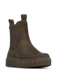 Botín de ante marrón con paneles laterales elásticos, lengüetas y suela gruesa estriada para mayor estabilidad. Textura suave y diseño de punta redondeada.