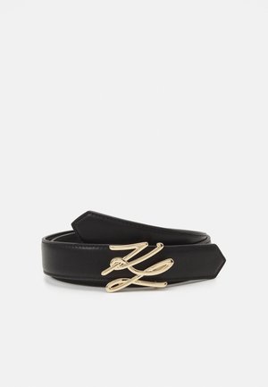 Black leather belt featuring a gold-tone, cursive buckle. The belt has a smooth texture with pointed ends.