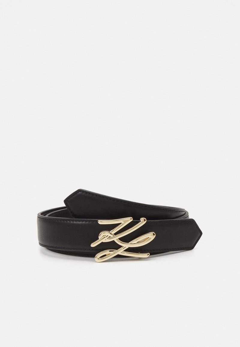 Ceinture en cuir noir avec une boucle en cursif dorée. La ceinture a une texture lisse et des extrémités pointues.