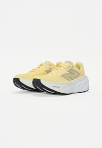 Gule atletiske sko med teksturert overmateriale, sølvlogo, polstret såle og kontrasterende svart yttersåle. Har snørebånd-design.