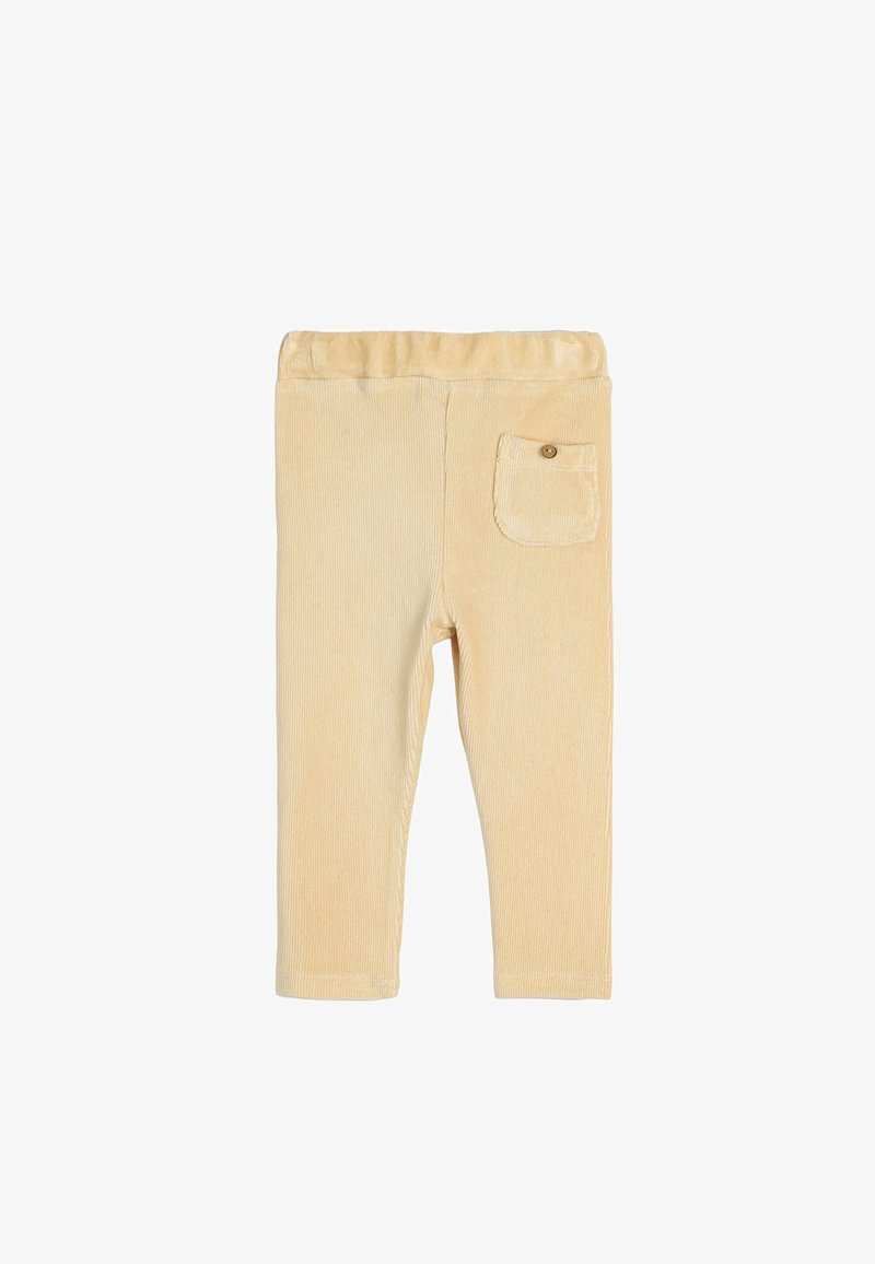 Pantalones de pana color beige claro con una textura suave, cintura elástica y un único bolsillo trasero tipo parche con un botón.