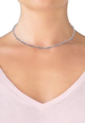 Collier en chaîne argentée avec maillons allongés et ovales porté autour du cou d'une personne, au-dessus d'un haut rose pâle à col en V.