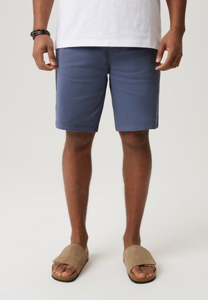 Granatowe szorty bawełniane o regularnym kroju, z bocznymi kieszeniami i gładką fakturą, zestawione z beżowymi sandałami wsuwanymi.