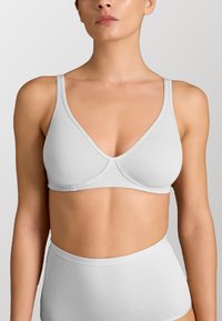 Bralette in cotone morbido grigio chiaro, con coppe triangolari, spalline sottili e una costruzione senza cuciture, caratterizzato da una leggera lucentezza e senza ferretto.