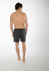 Pantaloni da nuoto neri con cintura elastica e dettagli delle tasche, mostrati su un modello maschile, visti da dietro. Texture liscia.