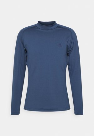 Chemise à col montant à manches longues couleur marine, fabriquée en tissu lisse et extensible, avec un logo discret sur la poitrine et des coutures à plat pour plus de confort.