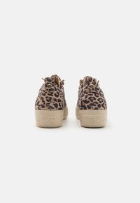 Trampki z zamszu w deseń lamparta z beżowymi gumowymi podeszwami, z pętelką i tłoczonym logo na pięcie. Widok z tyłu pokazuje szczegóły sznurowania.