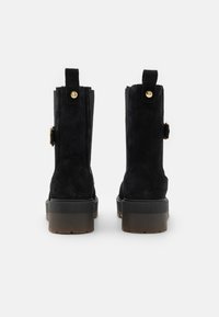 Czarne zamszowe botki za kostkę z gruboziarnistą platformą, z złotymi akcentami i pętelkami z tyłu dla łatwego zakładania.
