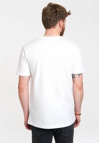 White cotton t-shirt with short sleeves and a crew neckline, featuring a straight hem and smooth texture, worn with black jeans.