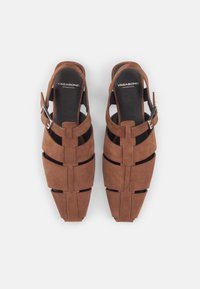 Barna velúr szandál, slingback kialakítással, bemetszett részekkel és fémcsattal az oldalon. Texturált felület és széles pántok.