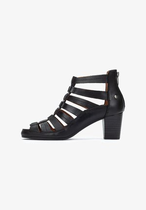 Sandale à talon en cuir noir avec un design de lanière découpée, dotée d'un dos fermé, d'un bout arrondi et d'un talon carré texturé.