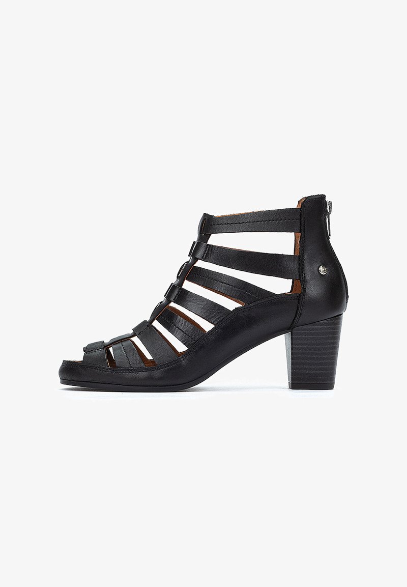 Sandalia de tacón de cuero negro con diseño de tiras recortadas, cuenta con una parte trasera cerrada, punta redonda y un tacón de bloque texturizado.