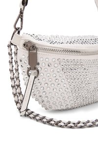 Bolso blanco con rhinestones plateados, cierre de cremallera y una correa de cadena. Presenta una superficie texturizada y una forma redondeada.