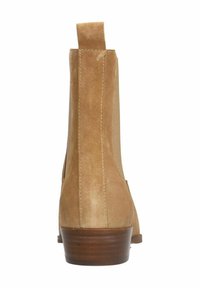 Tan suede enkellaars met een lage, gestapelde houten hak. Voorzien van een trekhaak aan de achterkant en elastische zijpanelen voor gemakkelijk aan- en uittrekken. Soepele textuur.