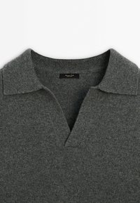 Pull en maille gris foncé avec un col en V à revers et des détails côtelés le long du col et de l'encolure.