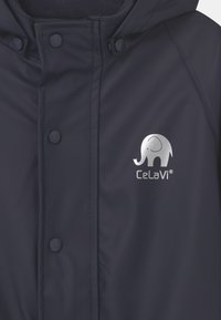 Granatowa wodoodporna kurtka z zatrzaskami, podszewką z polaru i logo srebrnego słonia. Gładka faktura z kapturem dla dodatkowej osłony.