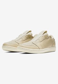 Beige Slip-On Sneaker aus glattem Leder mit abgerundeter Zehenpartie, perforierten Details und prominentem Seiten-Swoosh-Logo. Strukturierte Gummisohle.