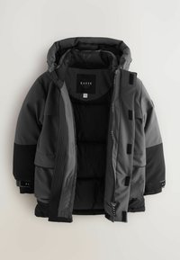 Padded coat v čiernej a tmavošedej farbe, s kapucňou, zipsovým zapínaním, viacerými vreckami a detailmi na suchý zips. Elegantný, textúrovaný dizajn látky.