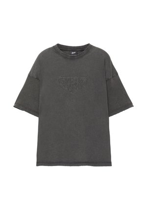 T-shirt oversized grigio scuro con maniche corte, colletto rotondo a costine e una grafica testurizzata al centro. Tessuto morbido, leggermente sbiadito.