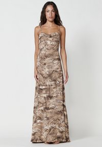 Brown maxi dress with spaghetti straps, featuring a fern pattern. Smooth fabric with a fitted bodice and flowing skirt.