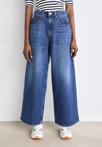 Vida vida blå denim jeans med hög midja, med knäppning, klassisk femfickdesign och en blekt tvätt.