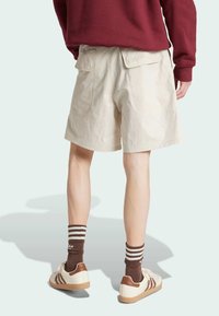 Bež pamučne šortse s dva stražnja džepa, nosi se s smešastim čarapama u smešastim šarama i belim patikama s smešastim detaljima.