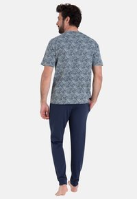 Ensemble de détente pour homme comprenant un haut à motifs bleus à manches courtes et un pantalon tapered navy. Tissu doux avec une coupe décontractée.
