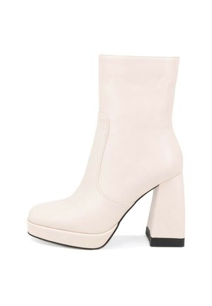 Stivaletto in pelle beige con tacco a blocco, punta arrotondata e cuciture minime. Presenta una superficie liscia e una suola piatta spessa.