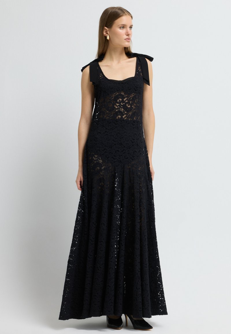 Sort blonde maxi kjole med en tætsiddende overdel, firkantet udskæring og skulderbånd. Den udskårne nederdel har detaljerede blonde mønstre og lag.