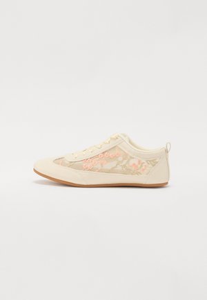 Chaussure beige avec broderie florale en rose et or ; présente une texture lisse, un bout arrondi et une semelle en caoutchouc avec une légère adhérence.