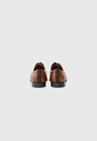 Zapatos de cuero marrón con un acabado suave, que presentan una raya marrón más oscura en la parte trasera, punta redonda y tacón bajo negro.