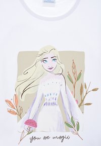 Camiseta blanca con un gráfico de un personaje con cabello largo y rubio, que viste un vestido blanco con acentos azules, rodeado de ilustraciones florales.