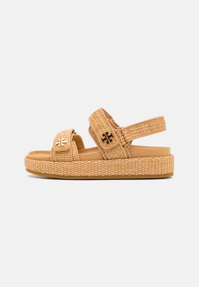 Sandale à plateforme tissée beige avec deux brides réglables et des accents de logo noirs et dorés sur fond blanc.