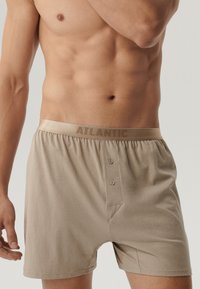 Beżowe bawełniane bokserki z miękkim elastycznym pasem, z logo "ATLANTIC" i zapięciem na guziki. Gładka tekstura i swobodny krój.