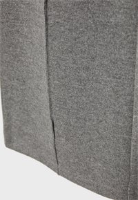 Gros plan sur un tissu tricoté côtelé gris avec un détail de couture verticale.