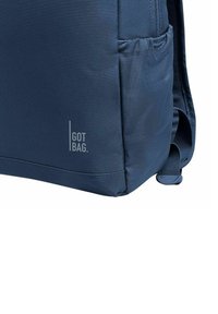 Blå tygryggsäck med texturerad yta, sidoficka och vertikal "GOT BAG."-logotyp. Robust remmar och förstärkta sömmar för hållbarhet.
