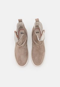 Botoșei de gleznă din suede maro deschis, cu o textură netedă, guler elastic, tabulator pentru a-i îmbrăca și talpă din cauciuc alb. Branding intern vizibil.