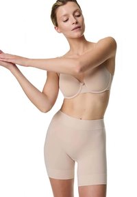 Beige bh og højtaljede formgivende shorts, der går til midt på låret. Glat, elastisk stof med sømløs konstruktion og uden synlige spænder.